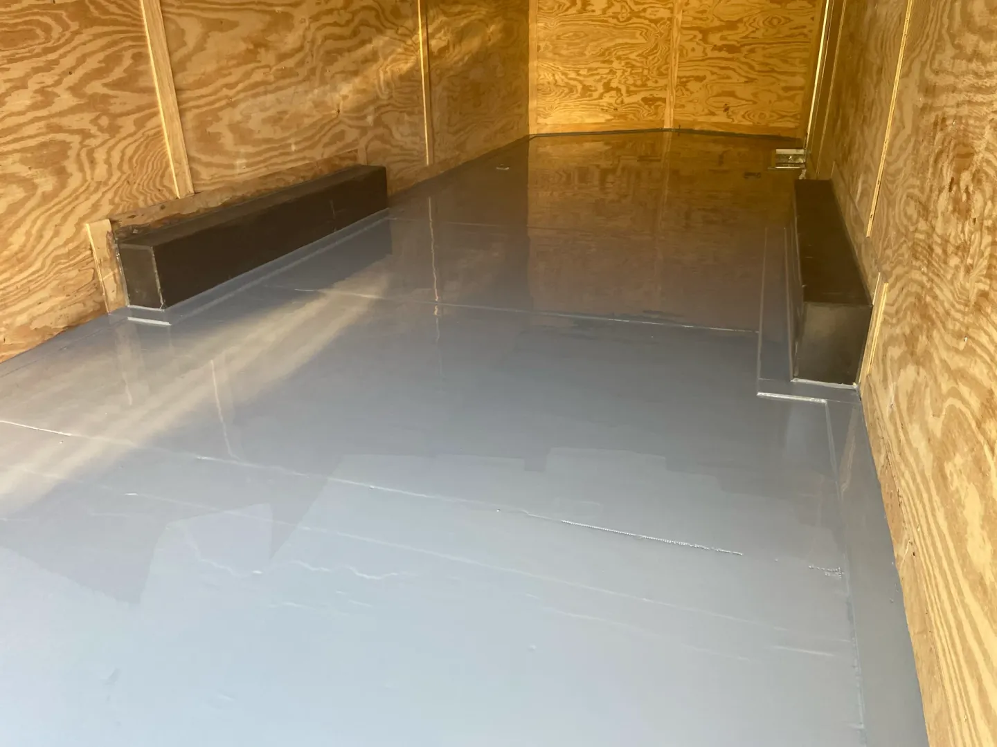 Coating work and reflective flooring inside an enclosed trailer.