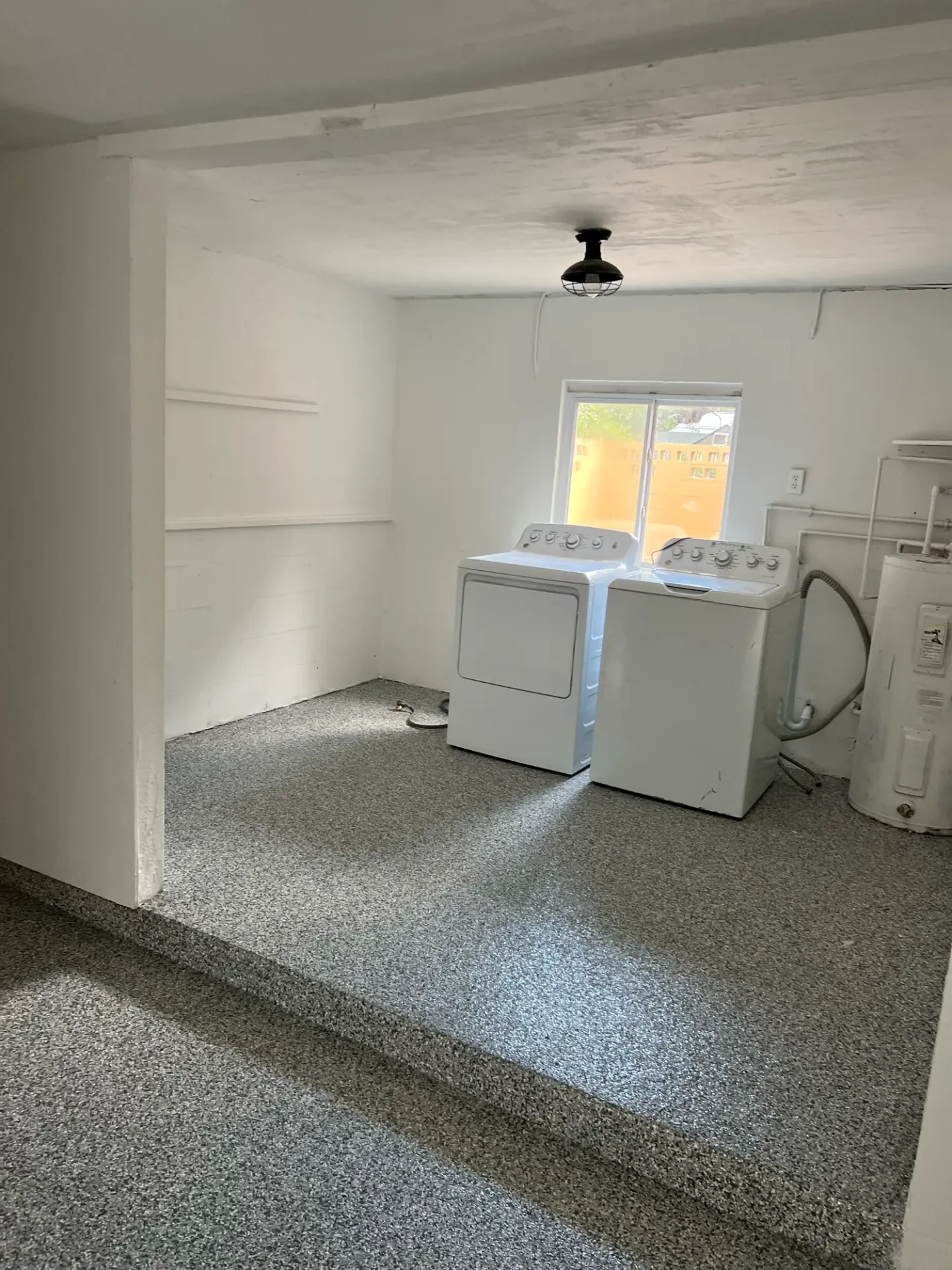 Speckled floor around laundry appliances and a raised step.