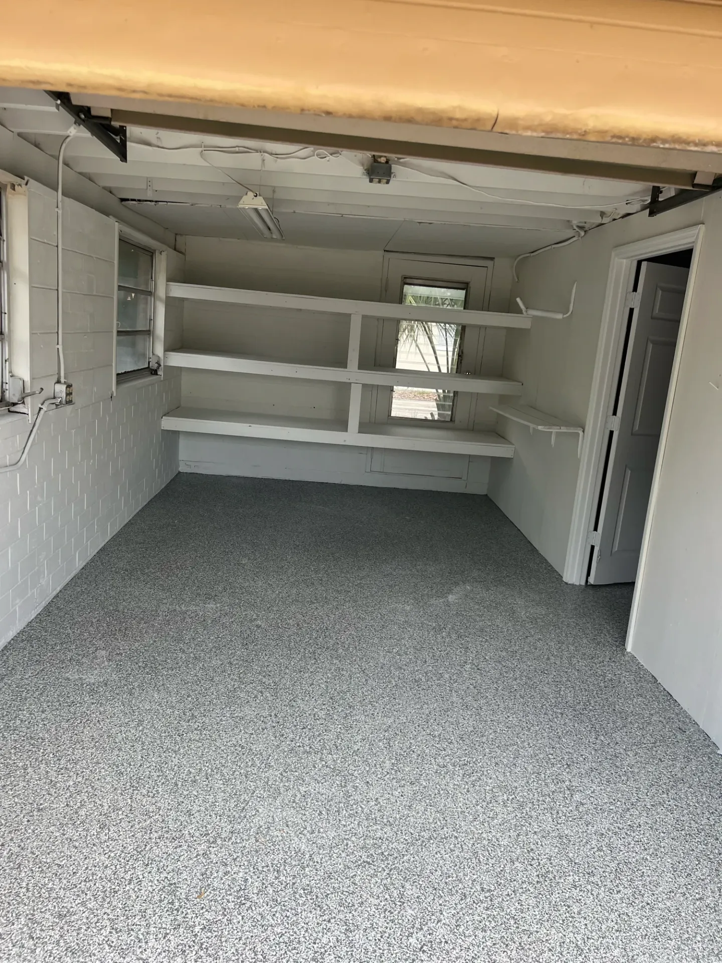 Gray speckled floor across a garage with built-in shelving.