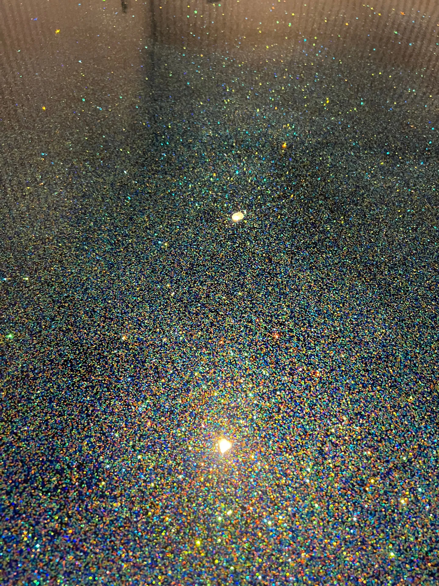 Reflective floor with multicolor speckled detail.